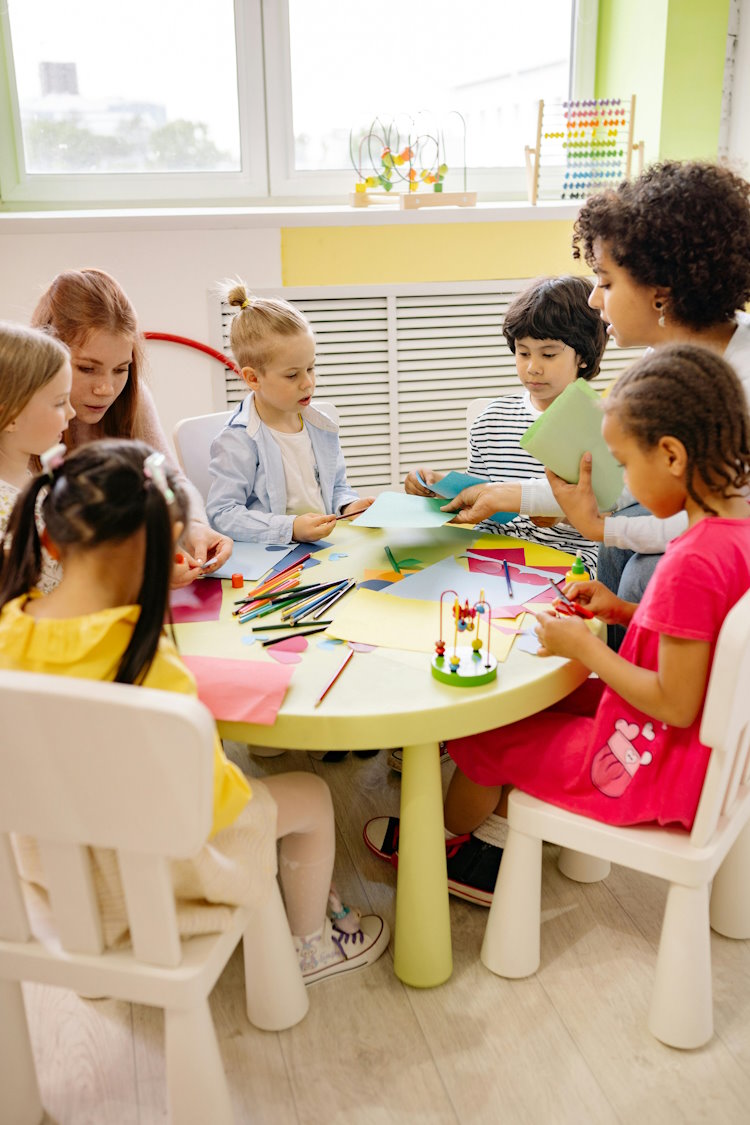 kids sitting around a table with teachers