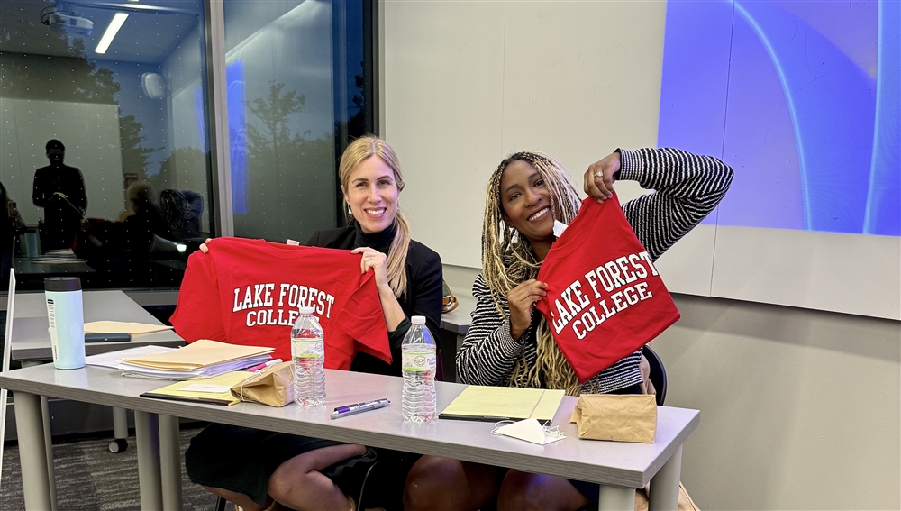 two women holding college sweatshirts