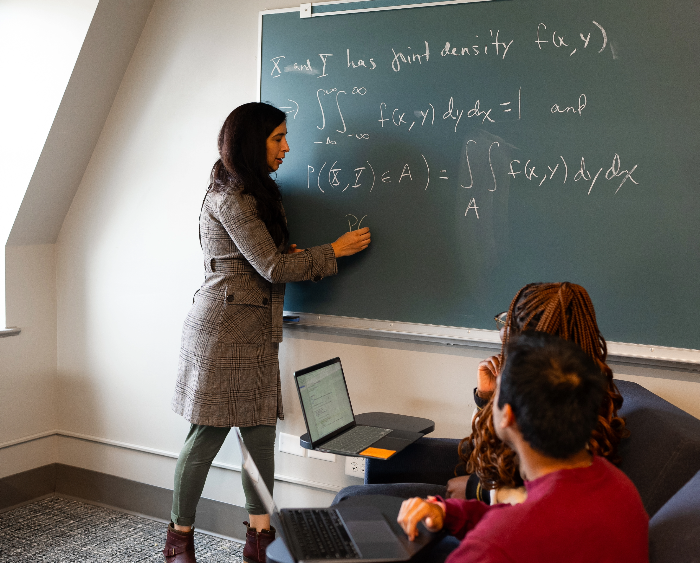 faculty member working with students by a blackboard