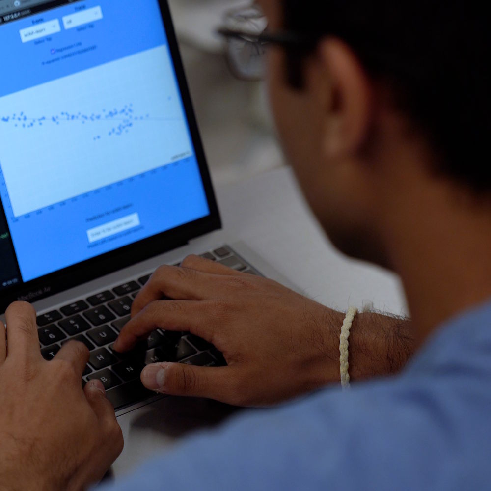 a student working on a laptop with graphs visible on screen
