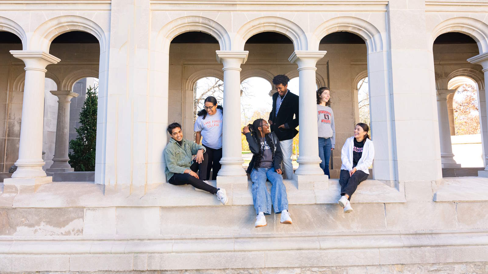 students standing and talking in a group of columns outdoors