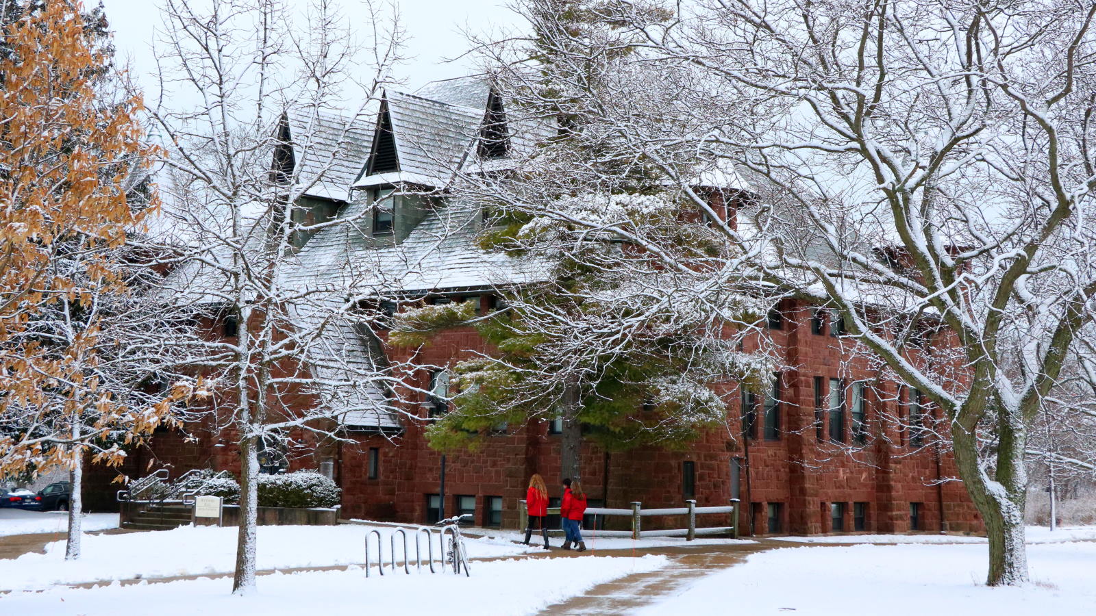 view of Hotchkiss hall covered in snow, two students walk in the foreground