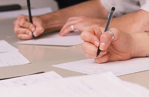 close up of  two sets of hands writing on paper