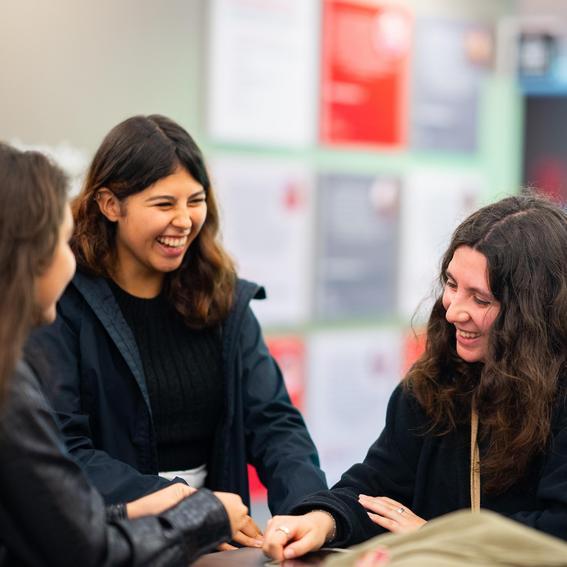 three students talking and laughing in a group