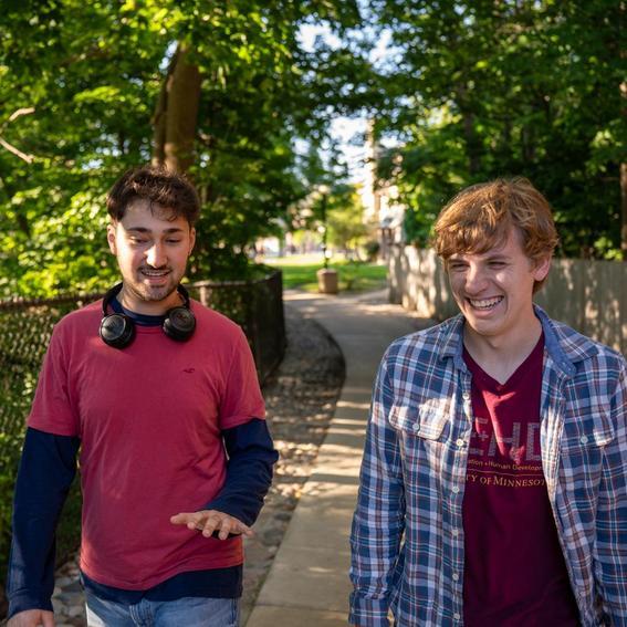 two students walking on a path on campus and laughing