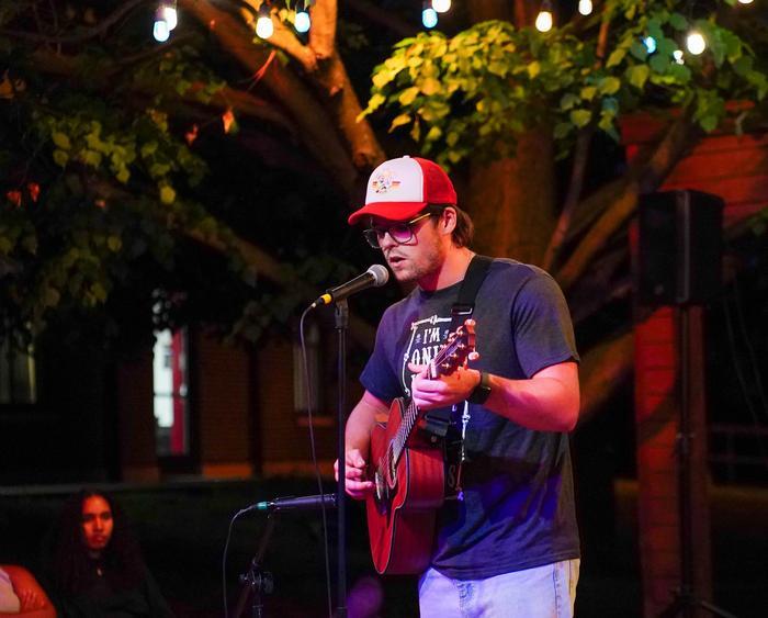 a student at an open mic event singing and playing guitar