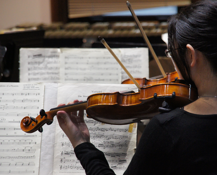 Close up of girl playing violin in orchestra