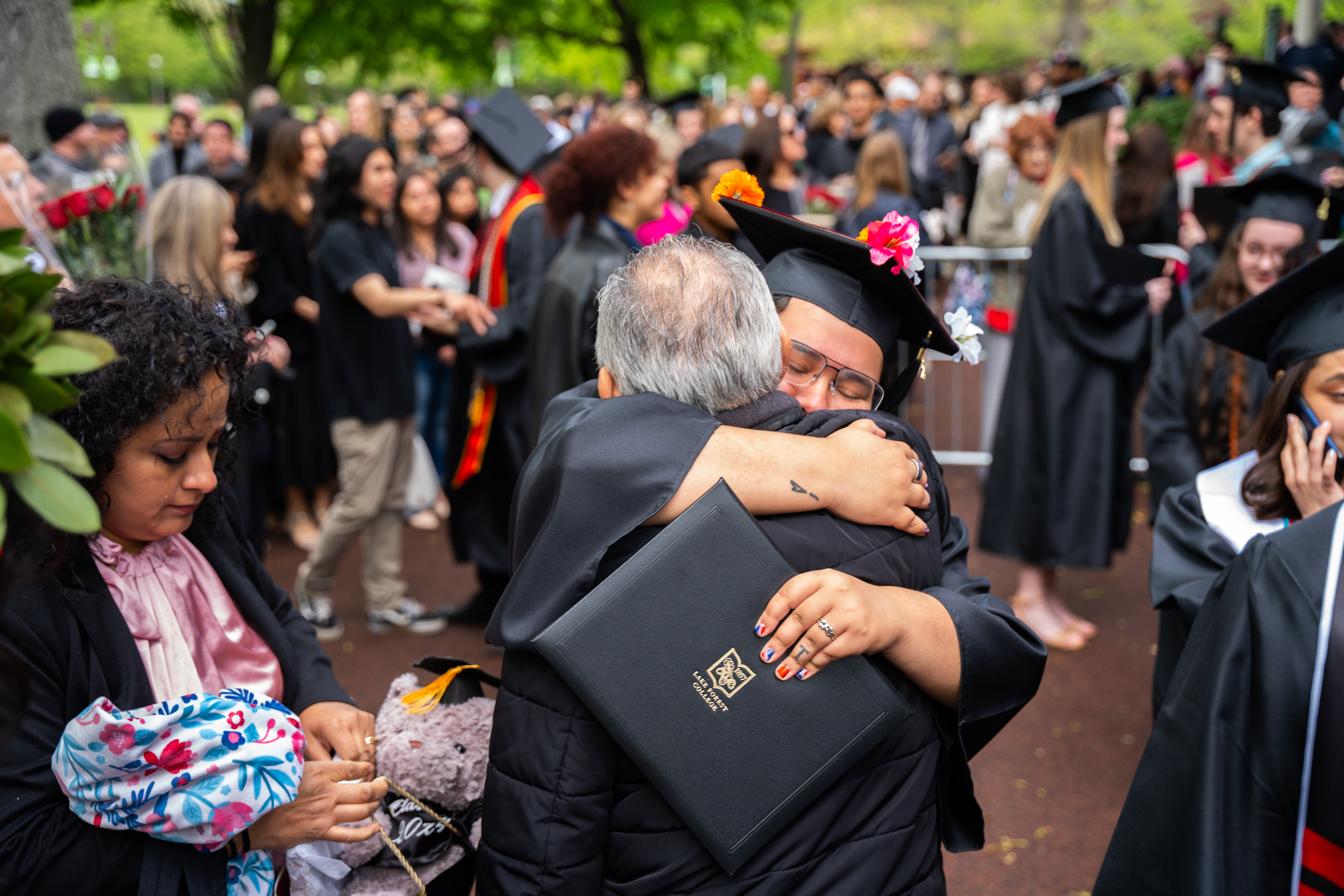 grad hugging guest outside commencement