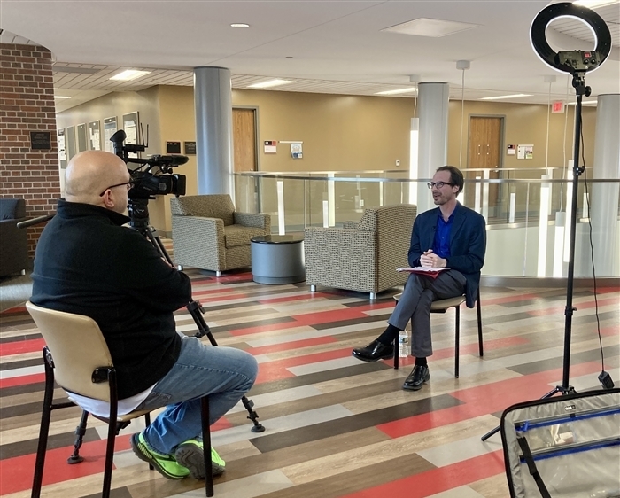 Seated man being interviewed on camera