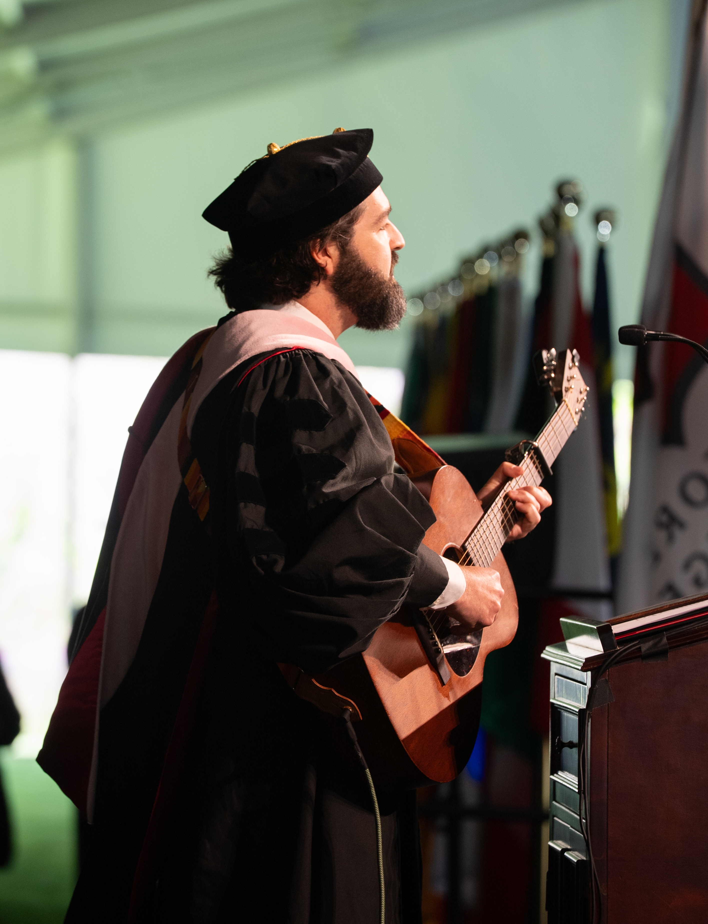 Man in graduation robes playing guitar