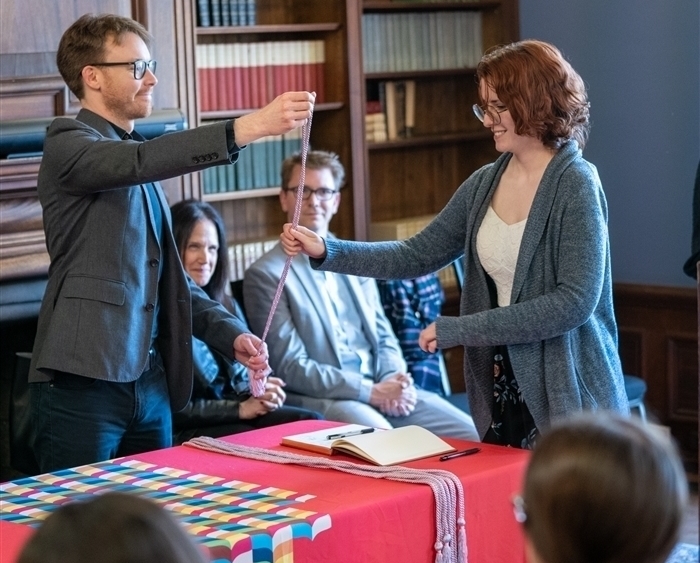 Student accepting PBK cord from professor at ceremony