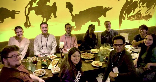 Students, professor and alums around restaurant table