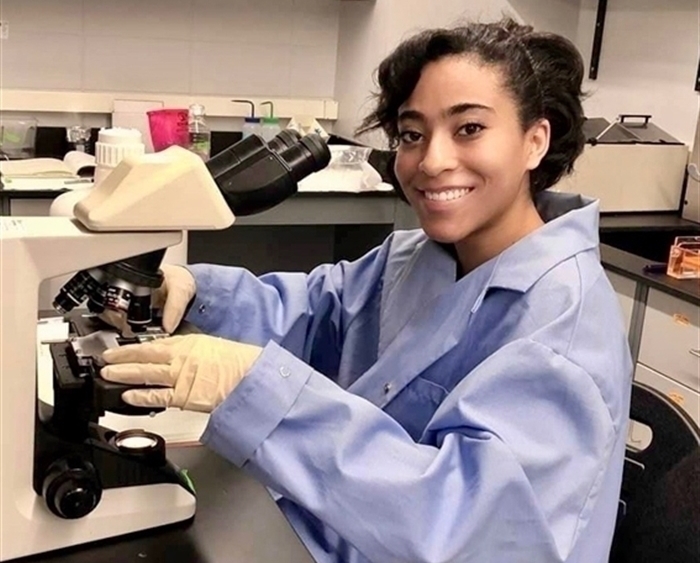 Portrait of Carris Borland in lab coat at microscope