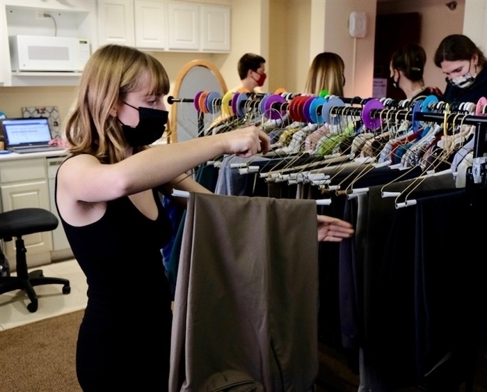 Sydni Foley rehanging a pair of slacks on a clothing rack