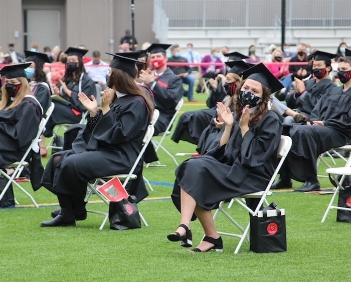 Socially distanced, masked graduates clapping