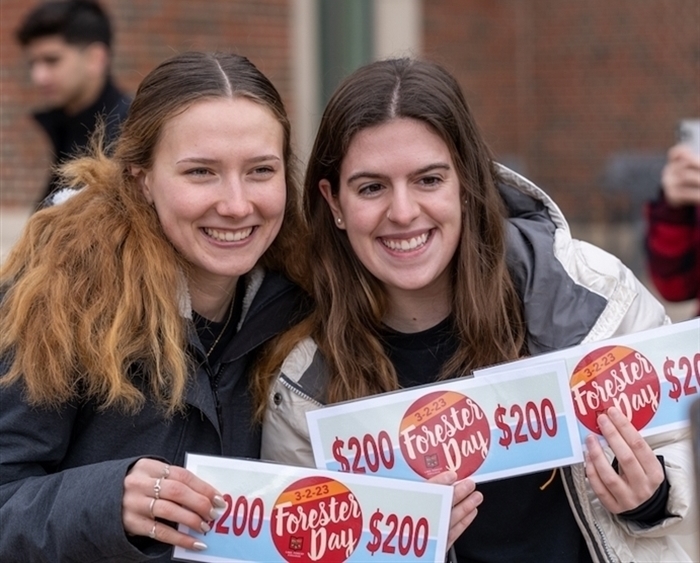 Two female students holding Forester Day pledges