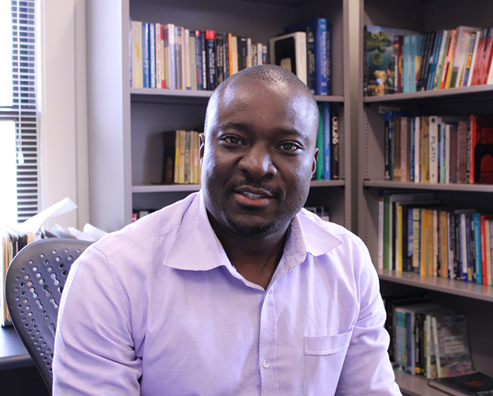 Desmond Odugu portrait in front of bookshelves