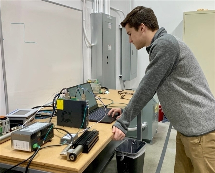 student working on computer attached to motor