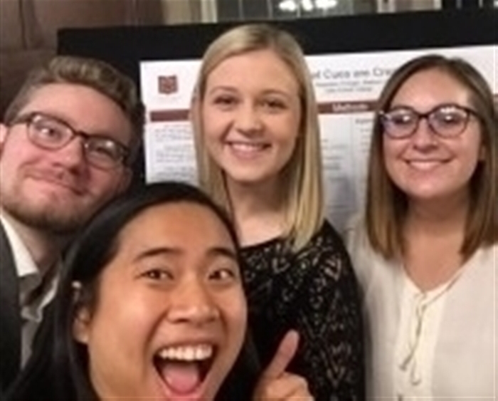 Four-student selfie in front of their research poster