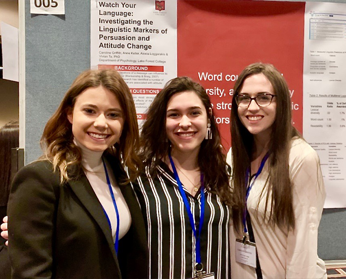 students in front of their research poster at conference