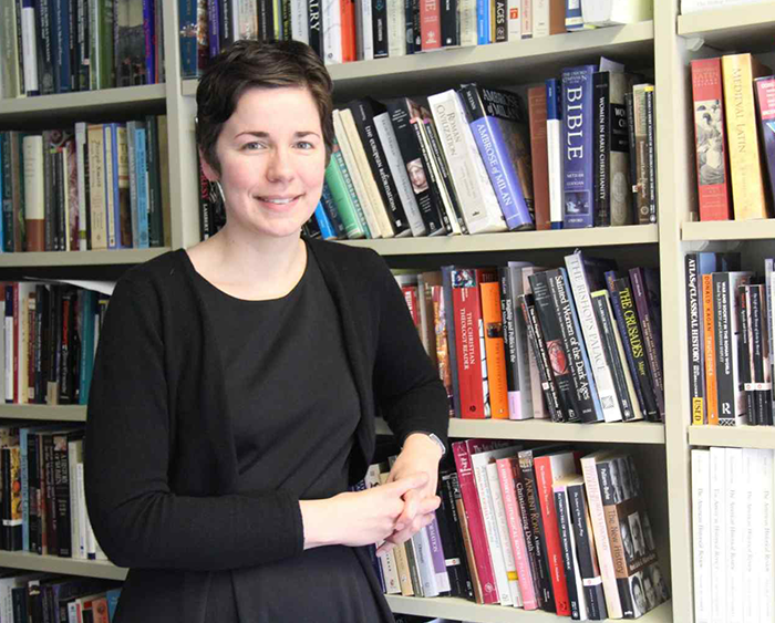 professor in front of book-filled shelves