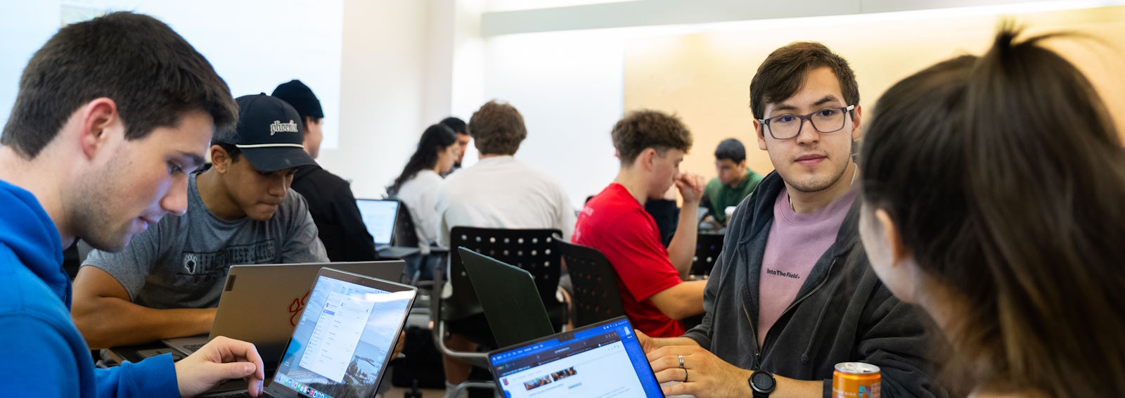 students working on laptops and discussing in a classroom