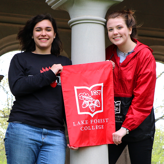 students holding a flag in front of pillars