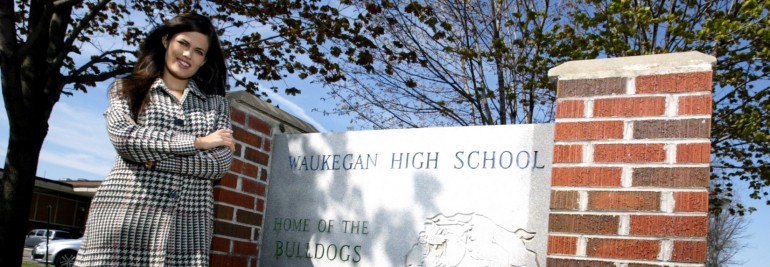 a teacher in front of a school's sign